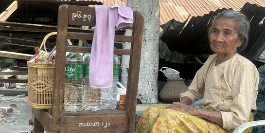Eine ältere Frau in Myanmar sitzt auf einem Plastikstuhl