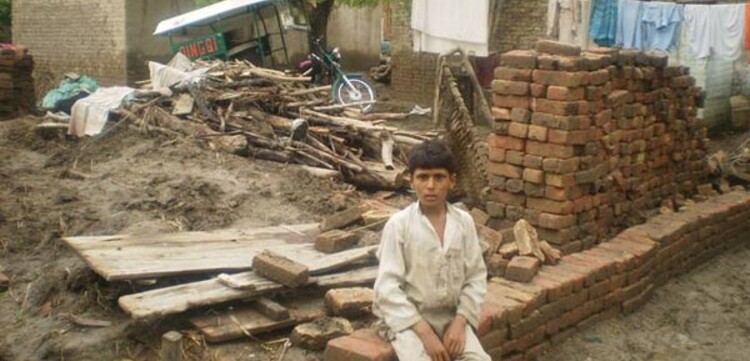 junge-auf-mauer Flut Pakistan: Junge baut ein Haus aus Ziegeln