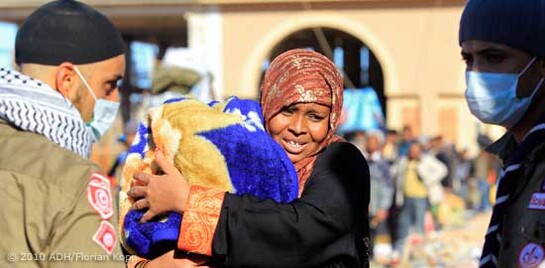 Eine Frau steht mit ihrem Kind in Libyen an der Grenze zu Tunesien