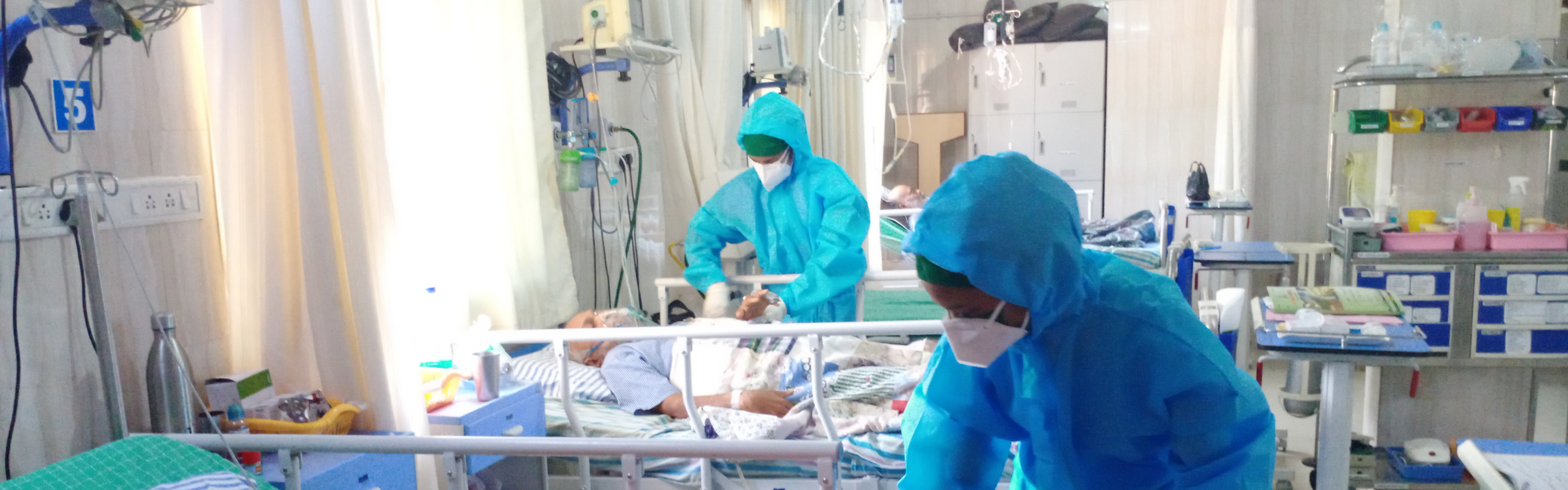 Eine Krankenschwester im Schutzanzug versorgt eine an Corona erkrankte Frau in einem indischen Krankenhaus
