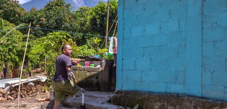 Ein Mann mit einer Beinprothese in Guatemala steigt eine Steintreppe zu seinem Haus empor 