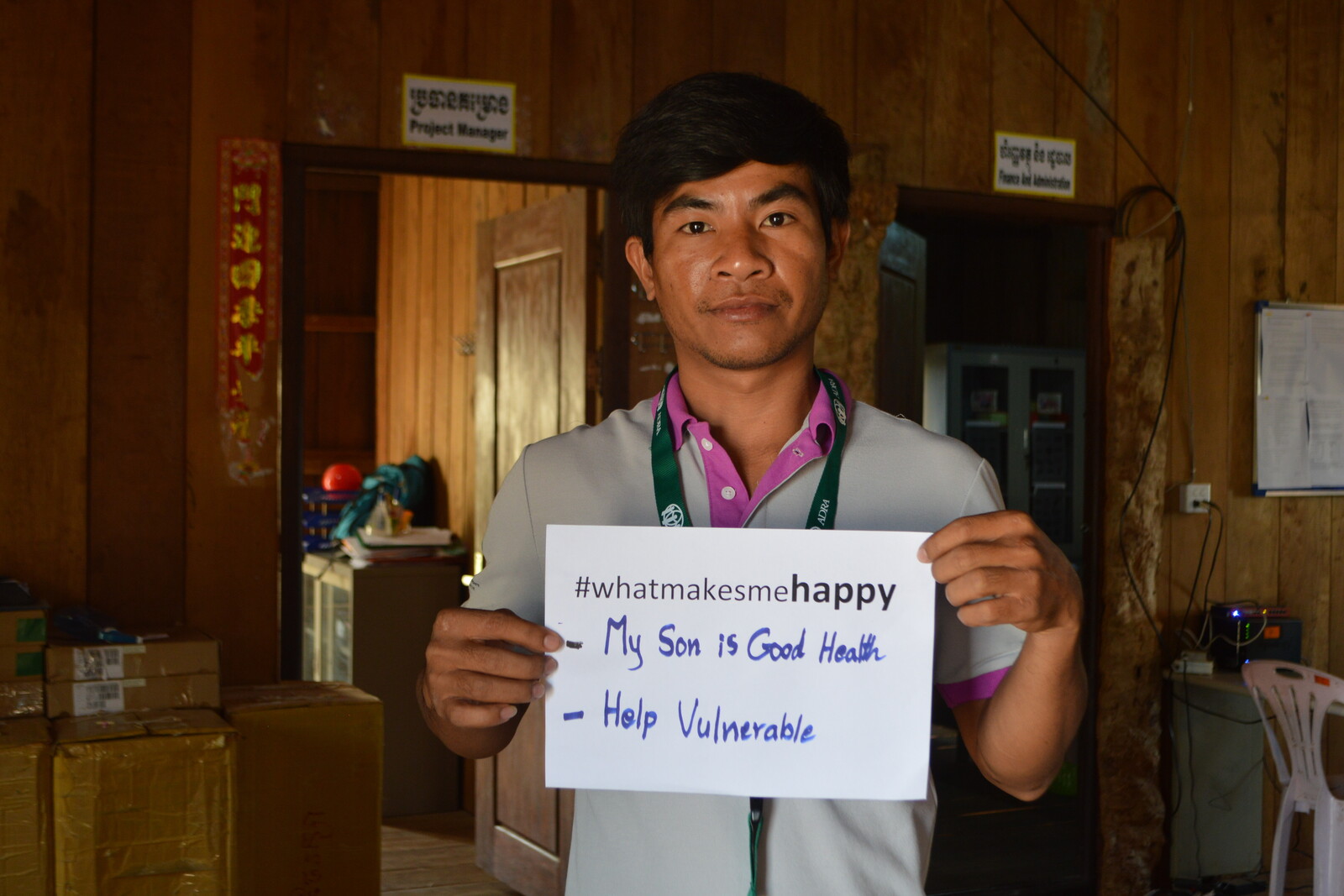 Ein Mann hält in Kambodscha ein Zettel hoch mit der Aufschrift "What Makes Me Happy - My son is good health / help vulnerable"