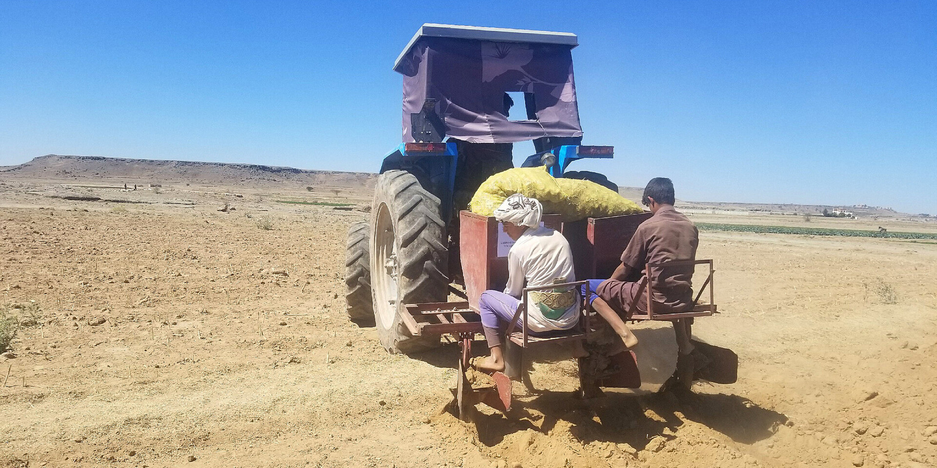 Zwei Menschen sitzen im Jemen auf einem Traktor Zwei Menschen sitzen im Jemen auf einem Traktor