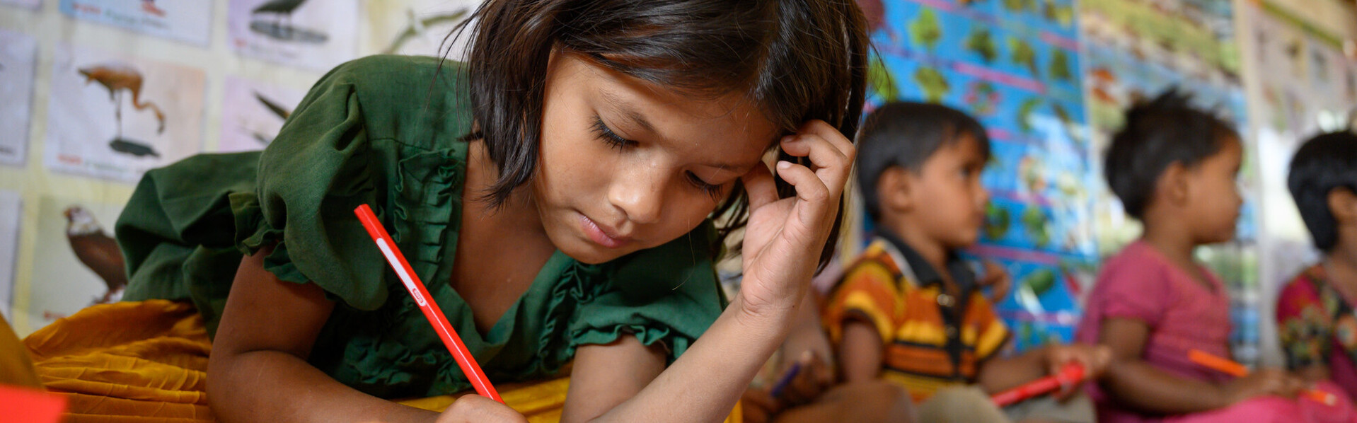 Ein Mädchen in Bangladesch löst Aufgaben in einem Schulbuch