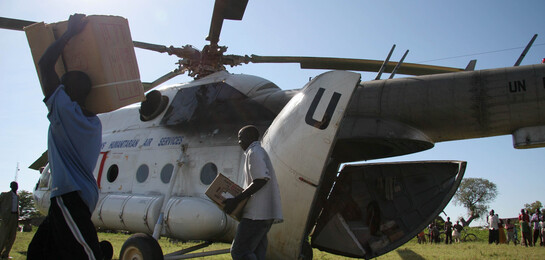 In Uganda werden nach der großen Flut Hilfsgüter aus einem Hubschrauber durch Männer ausgeladen.