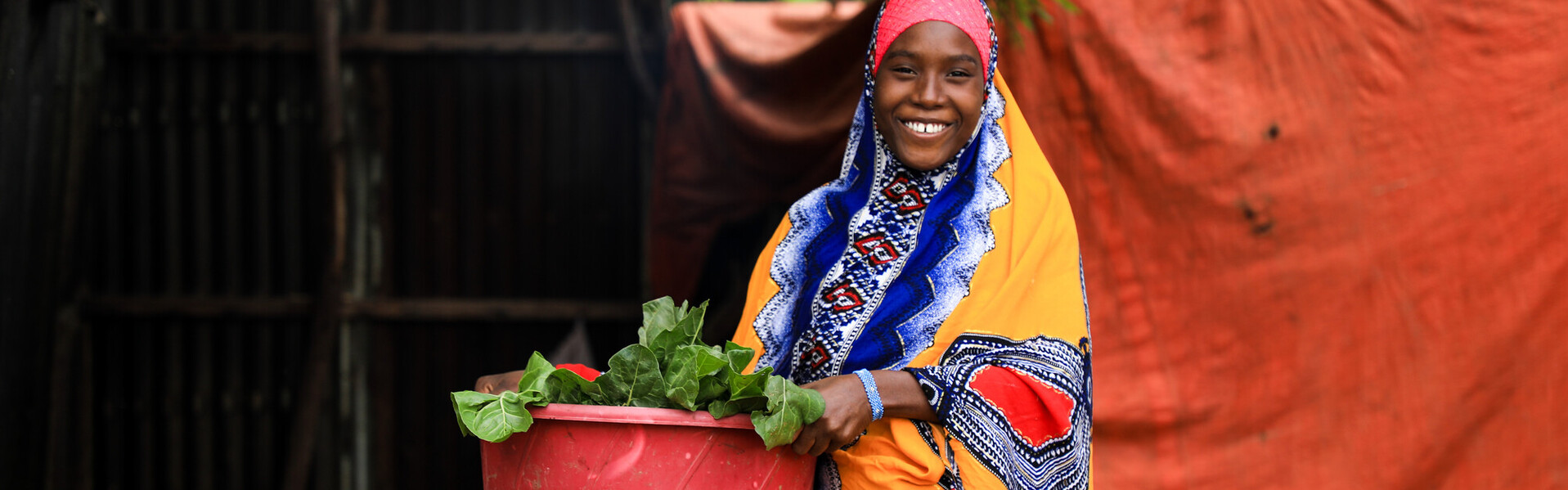 Eine Frau in Somalia trägt eine rote Schüssel mit Gemüse