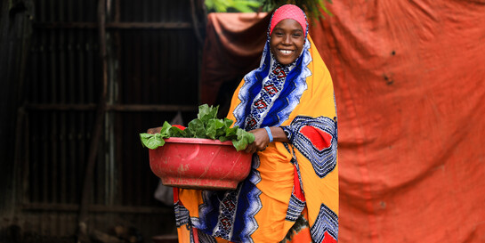 Eine Frau in Somalia trägt eine rote Schüssel mit Gemüse