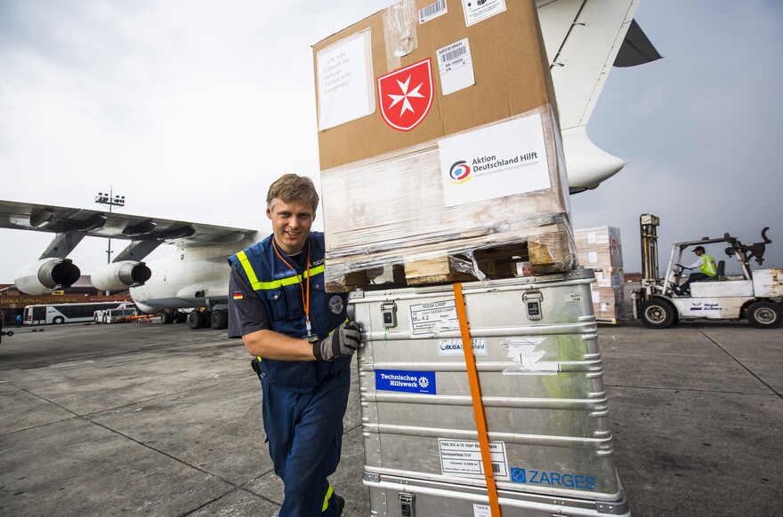 Ein Mitareiter nimmt am Flughafen Hilfsgüter entgegegen.