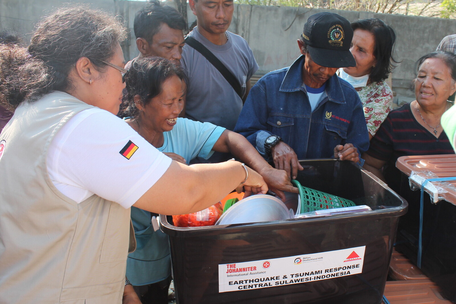 Eine Helferin verteilt Hilfsgüter an Menschen, die bei der Naturkatastrophe in Indonesien alles verloren haben