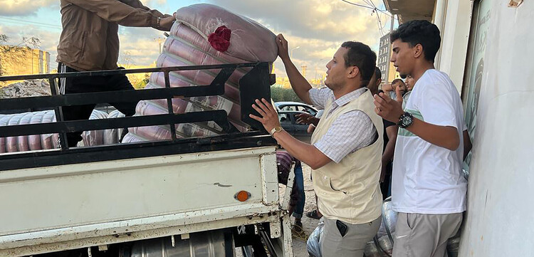 Drei Männer bei der Entladung von Hilfsgütern aus einem Truck in Libyen Drei Männer bei der Entladung von Hilfsgütern aus einem Truck in Libyen