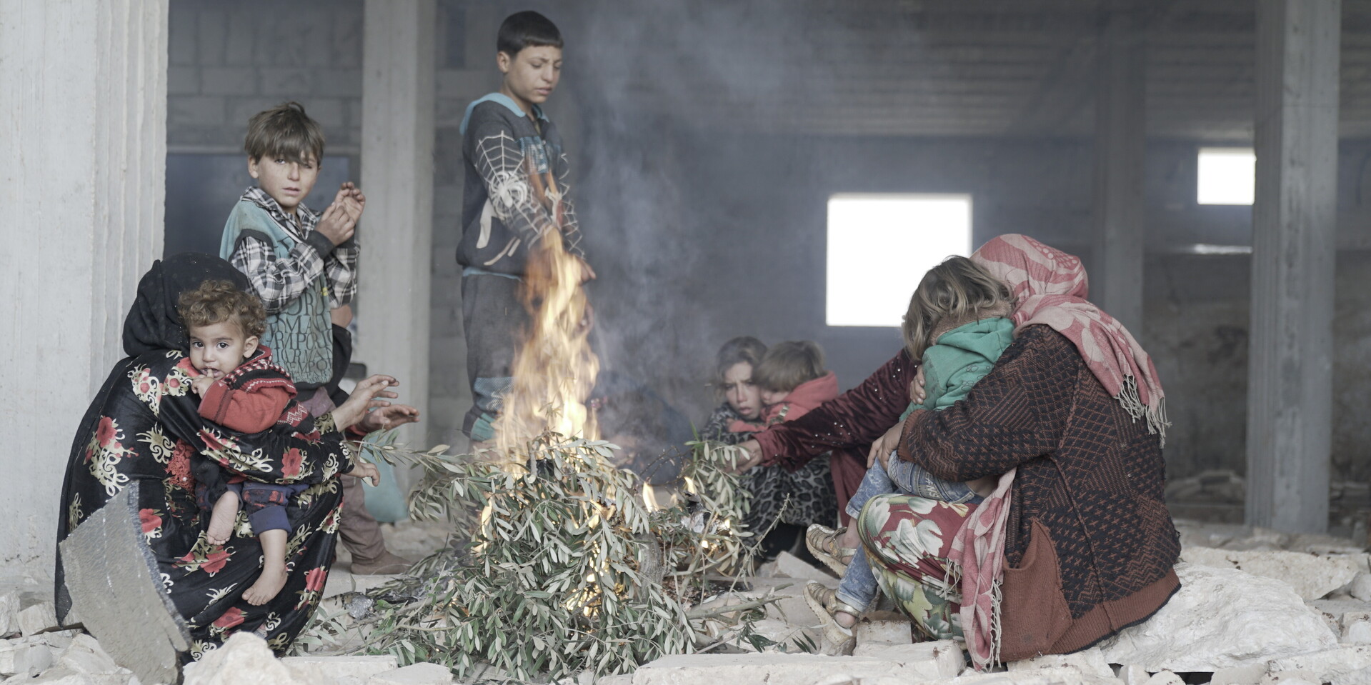 Mariams Familie und weitere geflüchtete Menschen wärmen sich an einem Feuer Mariams Familie und weitere geflüchtete Menschen wärmen sich an einem Feuer