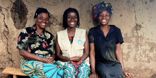 Beatrice (links) mit Tochter Rose (rechts) und einer Helferin von Handicap International (Mitte) vor ihrem neuen Haus in Uganda