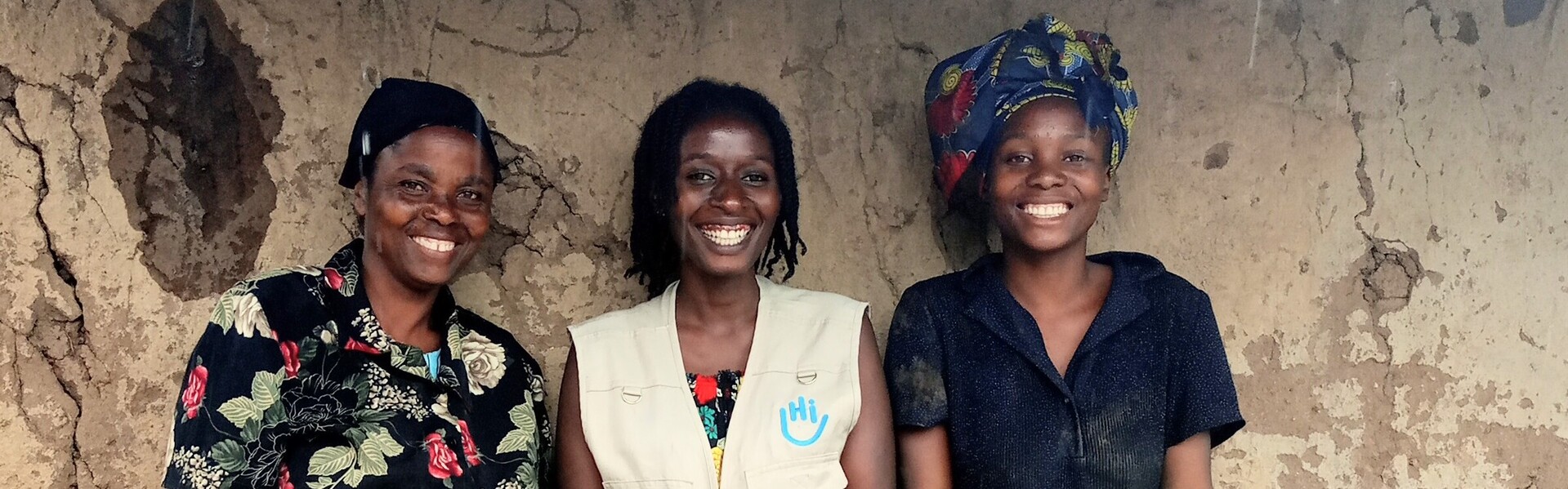Beatrice (links) mit Tochter Rose (rechts) und einer Helferin von Handicap International (Mitte) vor ihrem neuen Haus in Uganda