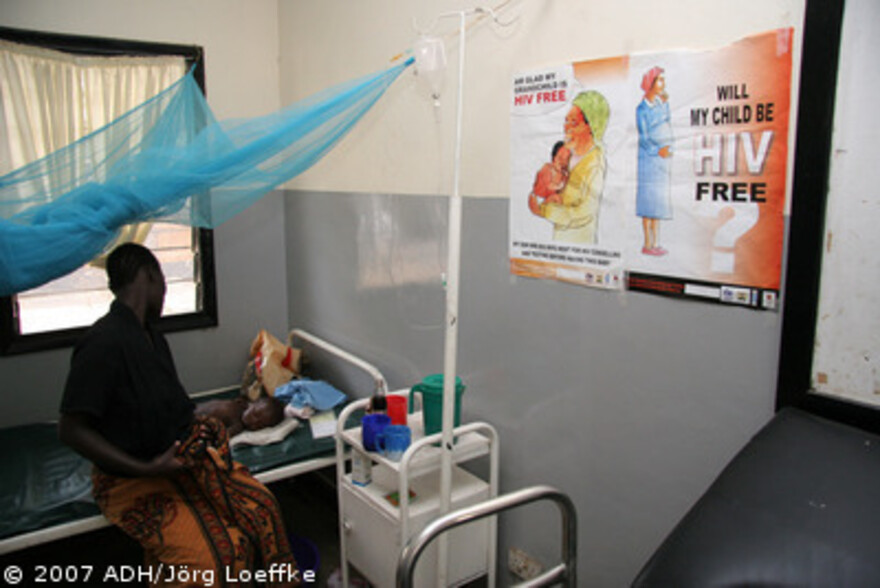 Flut Afrika: Mutter mit Kind neben HIV Plakat