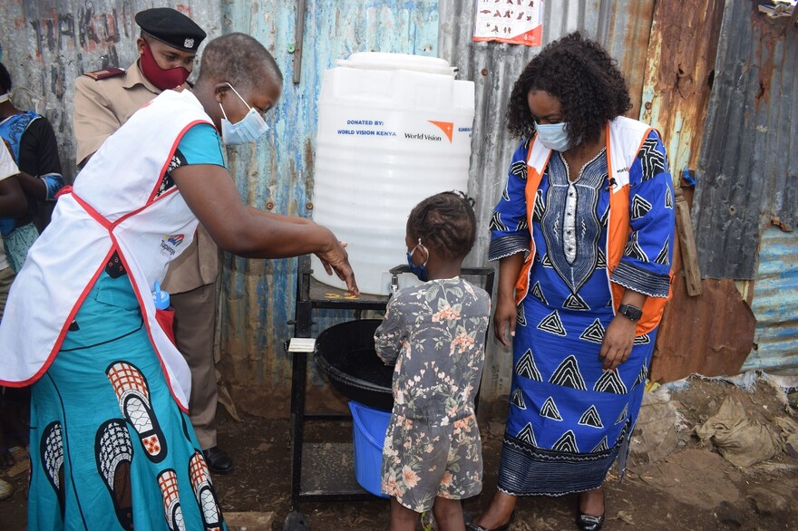 Helferinnen in Kenia mit einem Kind beim Händewaschen Helferinnen in Kenia mit einem Kind beim Händewaschen