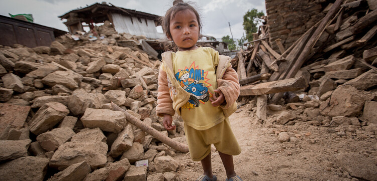 Ein kleines Mädchen inmitten der Zerstörung, die ein Erdbeben 2015 in Nepal hinterließ.