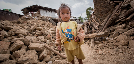 Ein kleines Mädchen inmitten der Zerstörung, die ein Erdbeben 2015 in Nepal hinterließ.