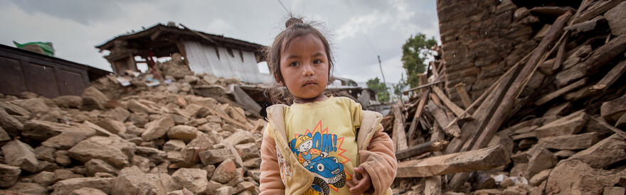 Ein kleines Mädchen inmitten der Zerstörung, die ein Erdbeben 2015 in Nepal hinterließ.