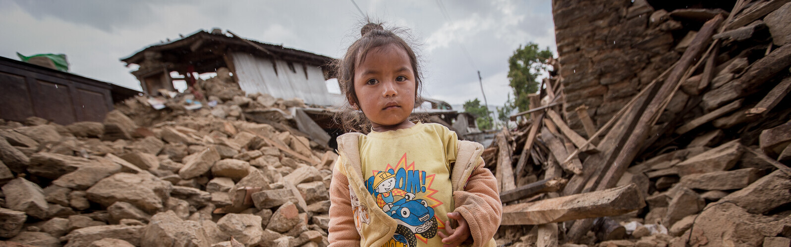 Ein kleines Mädchen inmitten der Zerstörung, die ein Erdbeben 2015 in Nepal hinterließ.