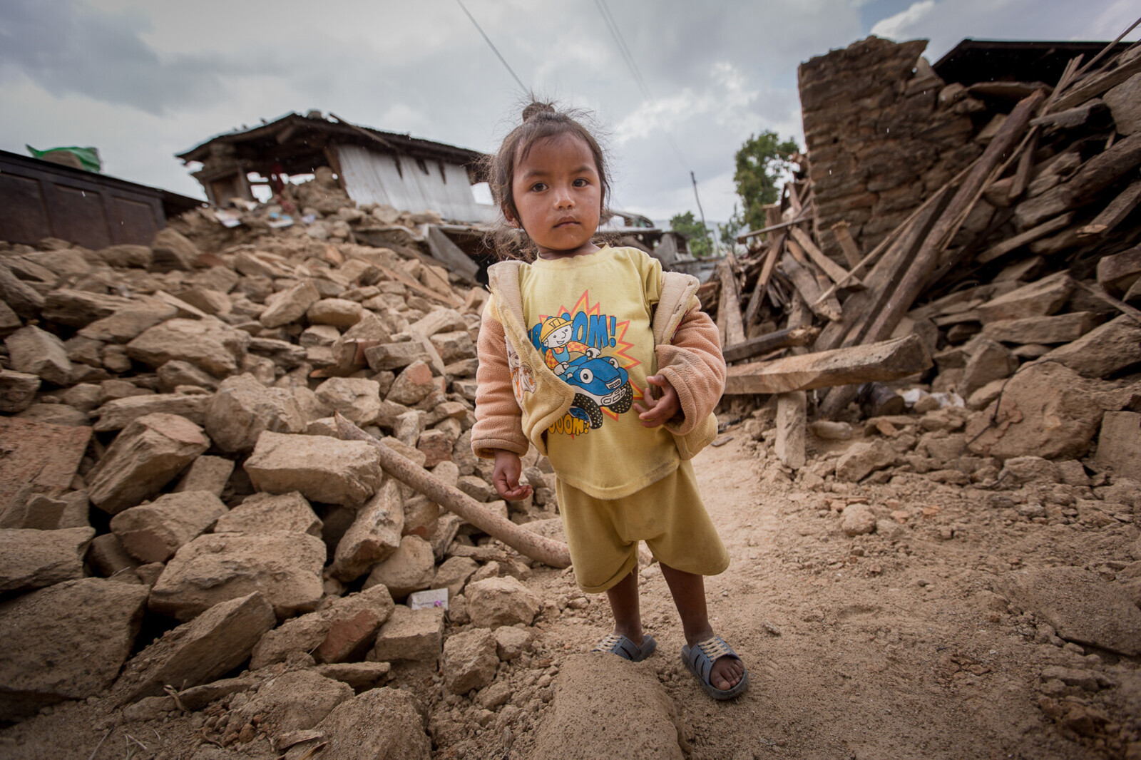 Ein kleines Mädchen inmitten der Zerstörung, die ein Erdbeben 2015 in Nepal hinterließ.