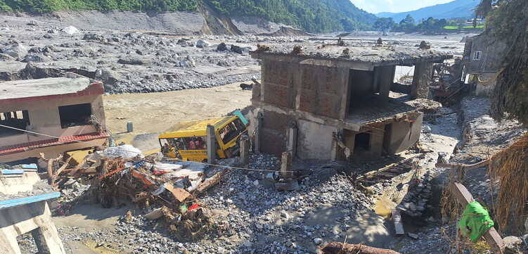 Zerstörte Gebäude und ein verschütteter Schulbus entlang des Flusses nach der Sturzflut in Nepal