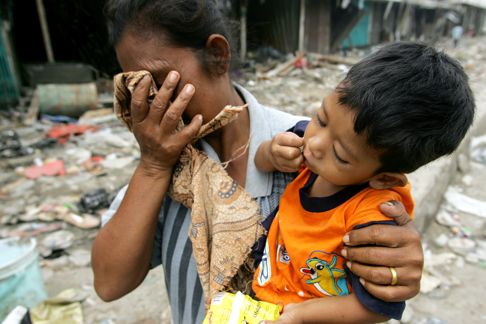 Tsunamis ereignen sich plötzlich und bringen Tod und Verwüstung. Eine Frau und ihr Kind stehen in den Trümmern, die einmal ihre Heimat waren.