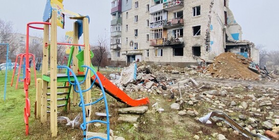 Ein von Bomben zerstörter Spielplatz und Wohnhaus in der Ukraine