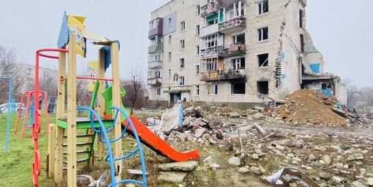 Ein von Bomben zerstörter Spielplatz vor einem Wohnhaus in der Ukraine