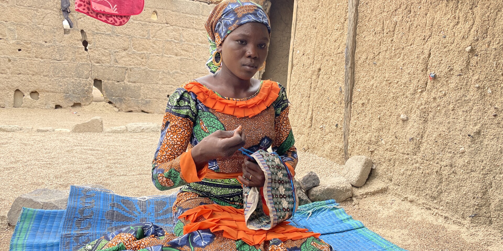 Halinka sitzt vor ihrem Haus im Geflüchtetencamp in Nigeria auf dem Boden Halinka sitzt vor ihrem Haus im Geflüchtetencamp in Nigeria auf dem Boden