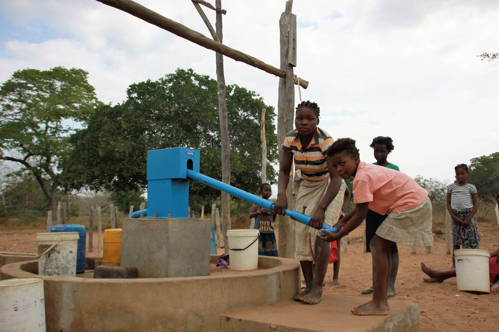Kinder pumpen Trinkwasser an einem Brunnen. Durch die Brunnen müssen die Menschen nicht mehr an Wasserlöchern Wasser schöpfen.