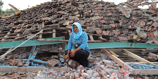 Eine Frau in Indonesien vor einem zerstörten Haus (Archivbild)