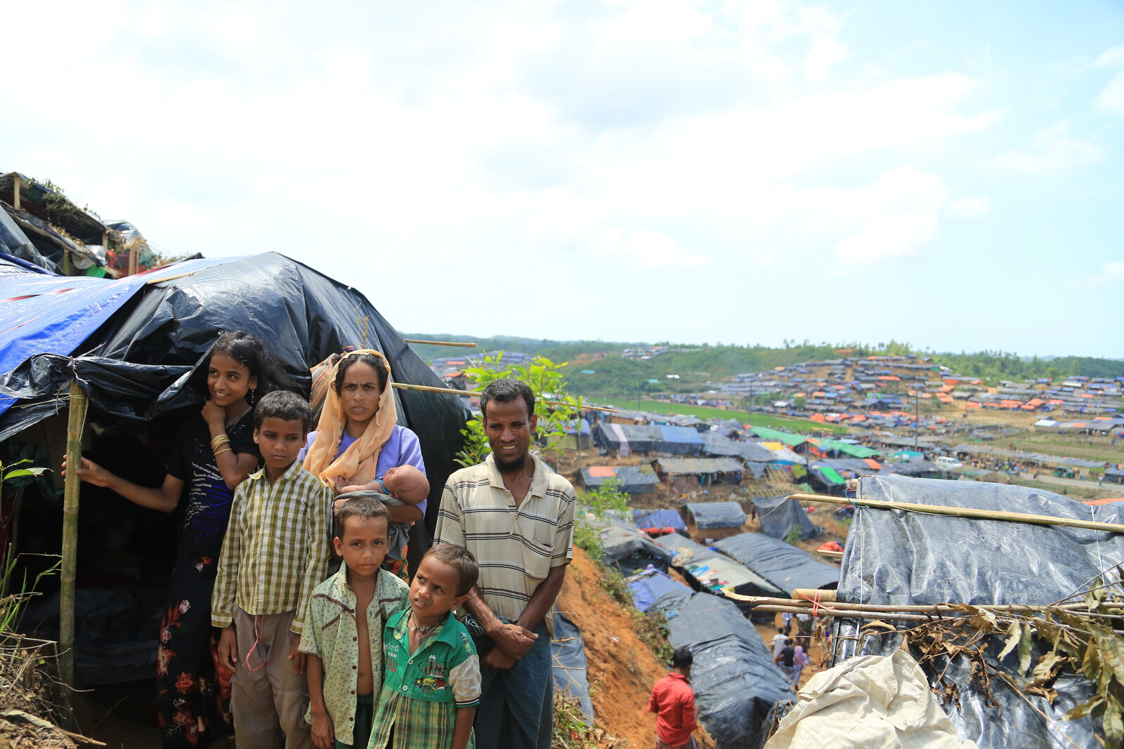 Eine aus Myanmar geflüchtete Familie steht vor ihrer Notunterkunft in einem Flüchtlingslager in Bangladesch