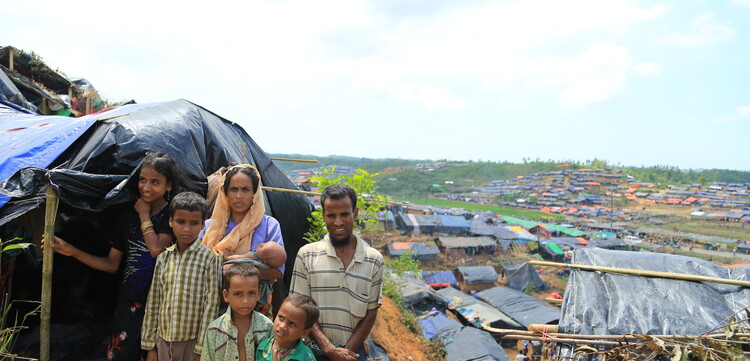 Eine aus Myanmar geflüchtete Familie steht vor ihrer Notunterkunft in einem Flüchtlingslager in Bangladesch Eine aus Myanmar geflüchtete Familie steht vor ihrer Notunterkunft in einem Flüchtlingslager in Bangladesch