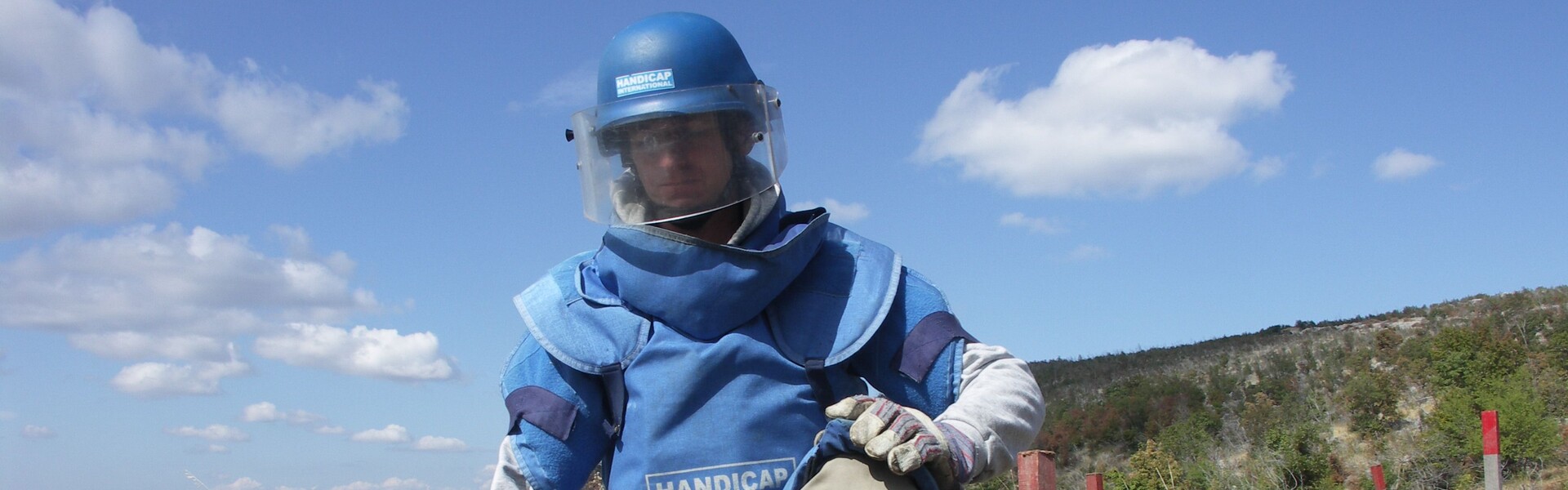 Ein Mann im Schutzanzug steckt ein Suchfeld zur Entminung ab