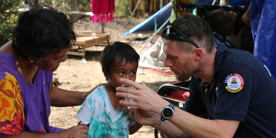 Ein Helfer der Organisation Bundesverband Rettungshunde versorgt ein Kind mit Trinkwasser