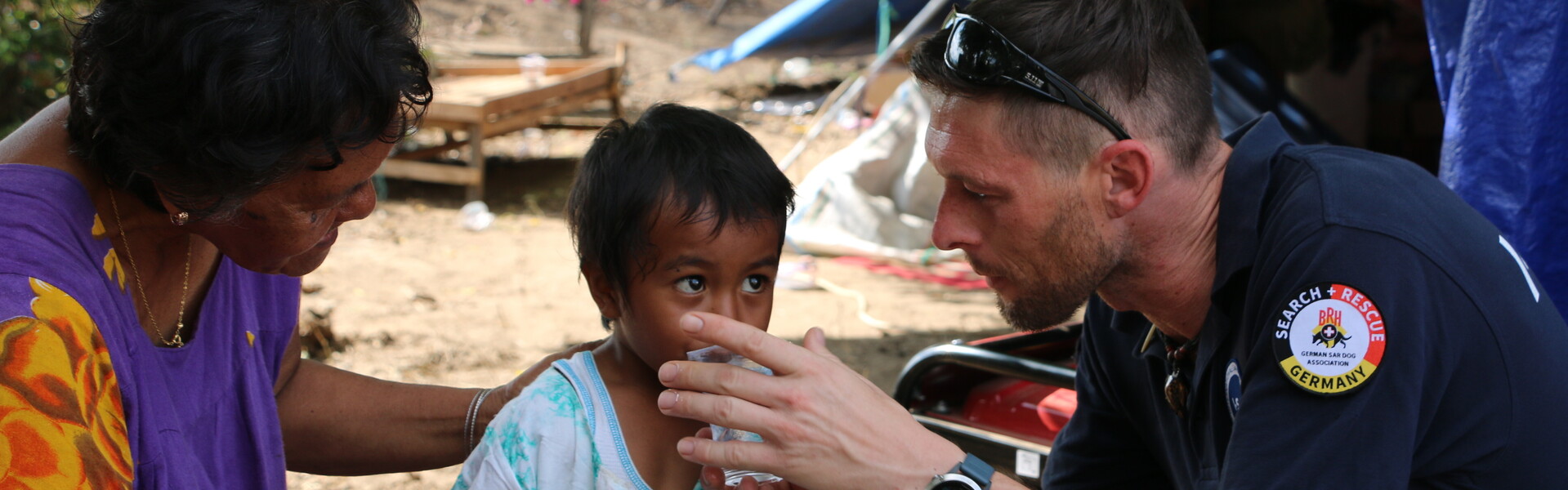 Ein Helfer der Organisation Bundesverband Rettungshunde versorgt ein Kind mit Wasser