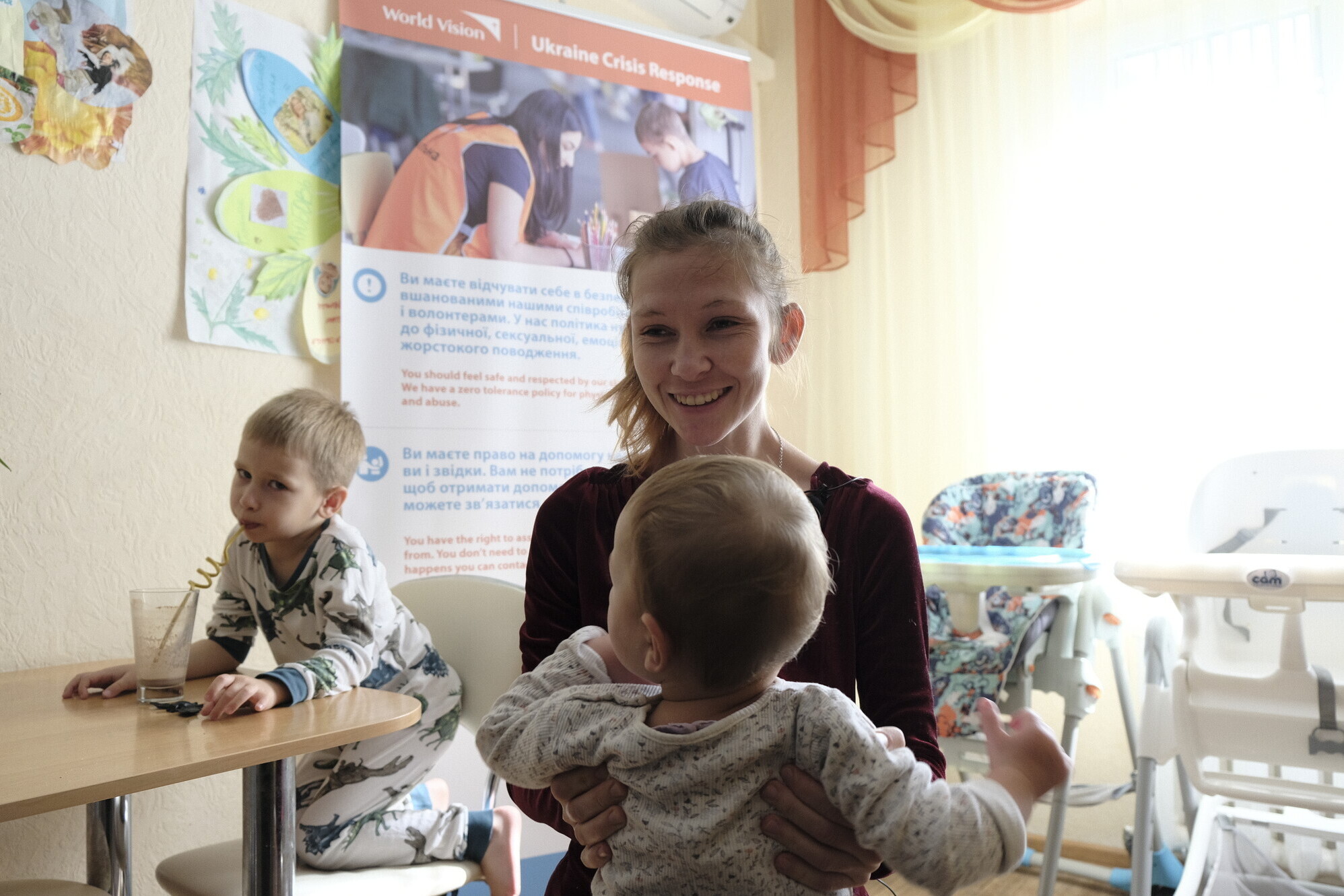 Eine Frau aus der Ukraine mit ihren Kindern bei einem Hilfsprojekt von World Vision