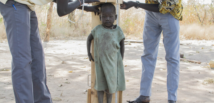 Helfer messen die Größe eines Mädchens in Kenia.