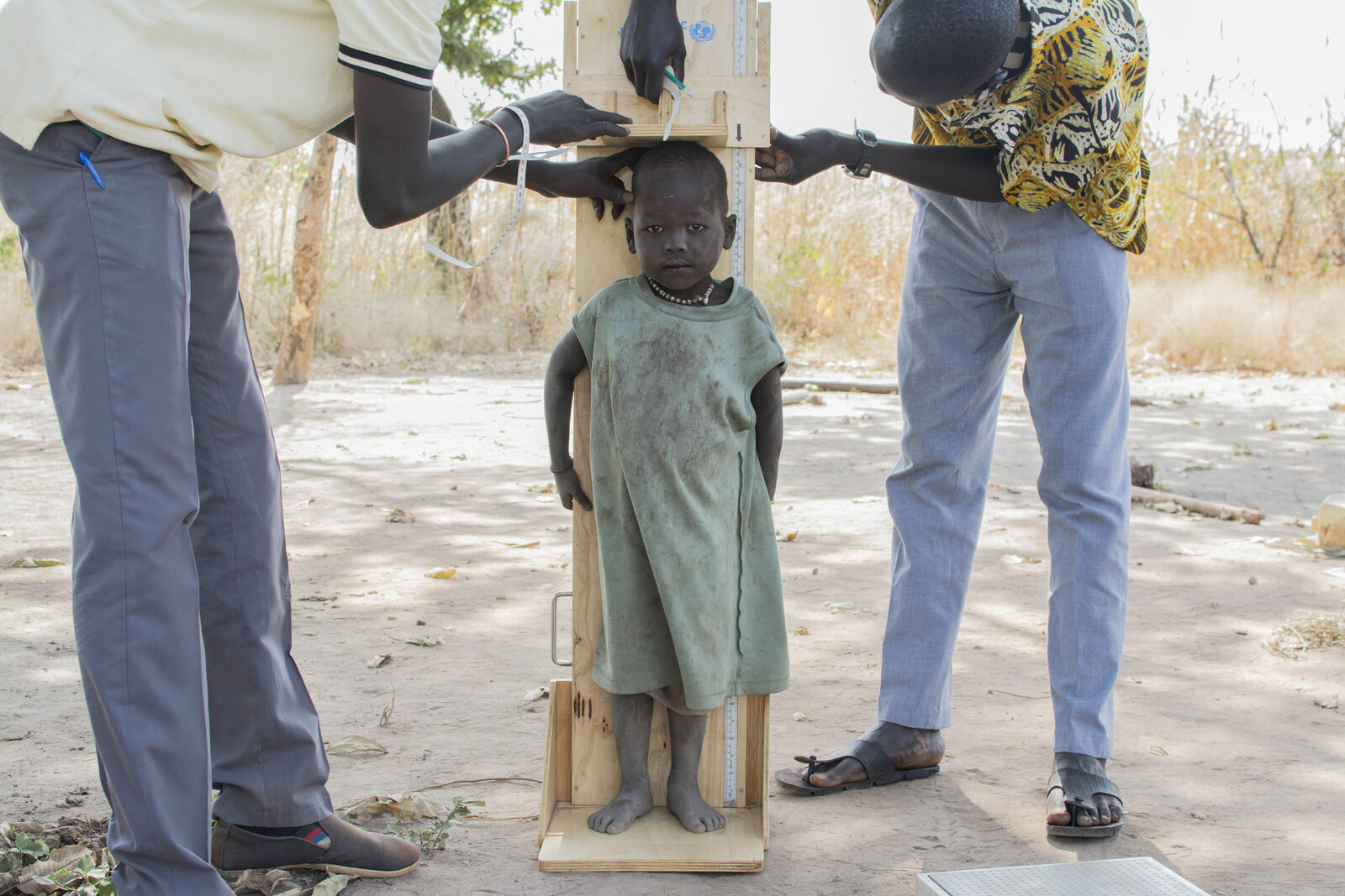 Helfer messen die Größe eines Mädchens in Kenia.
