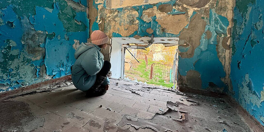 Ein Kind schaut aus dem Fenster einer zerstörten Schule in der Ukraine