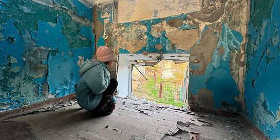 Ein Kind schaut aus dem Fenster einer zerstörten Schule in der Ukraine