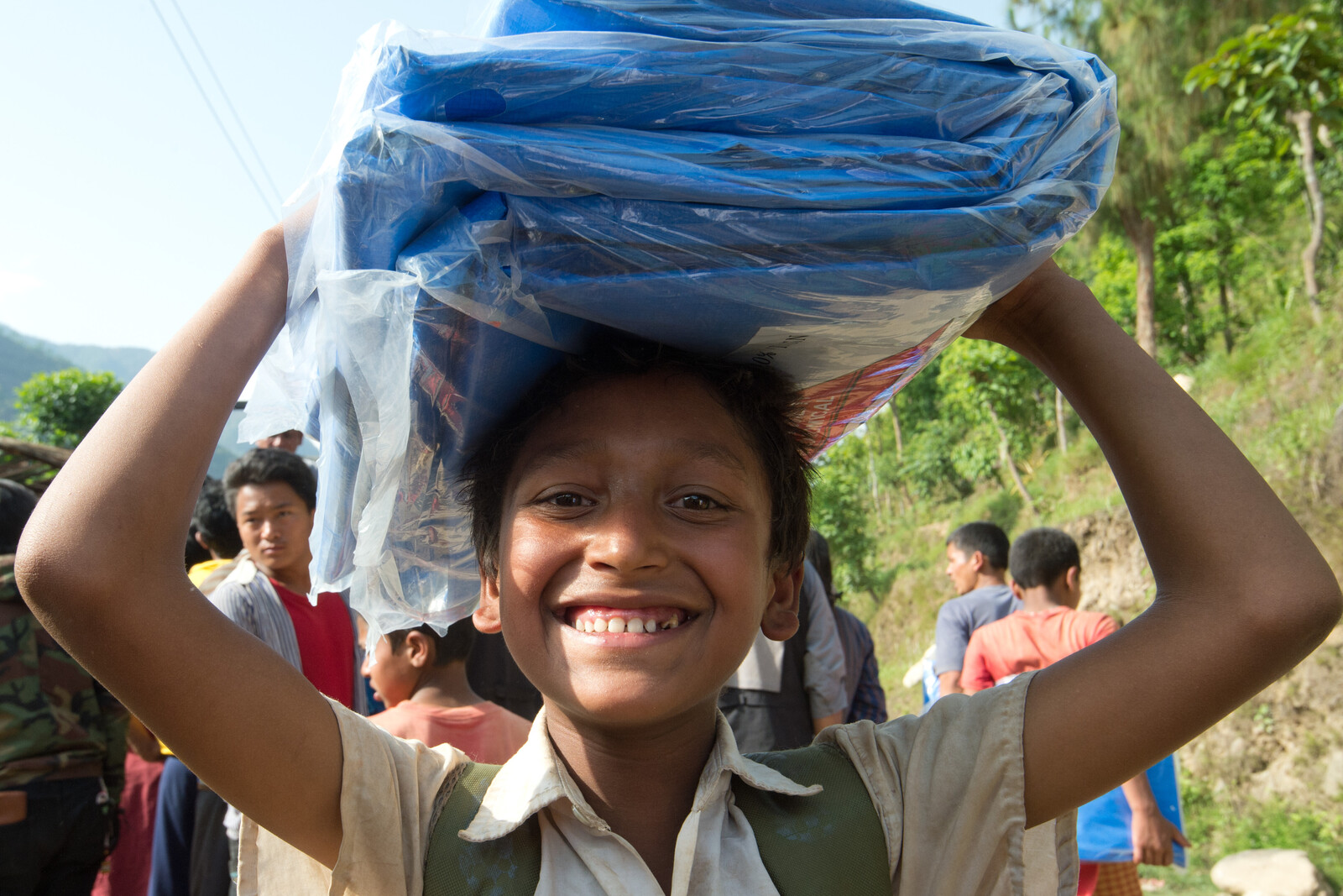 Ein Kind trägt einen Sack zum Schutz vor Monsun in Nepal.