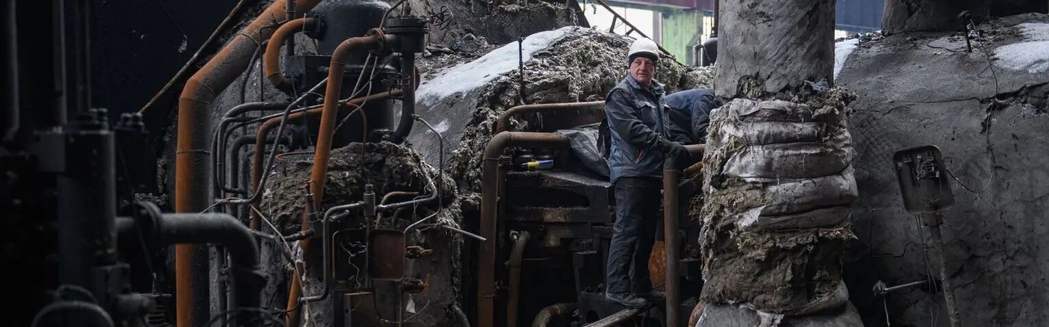 Ein Mann steht in der Ukraine inmitten einer zerstörten Anlage zur Energieversorgung