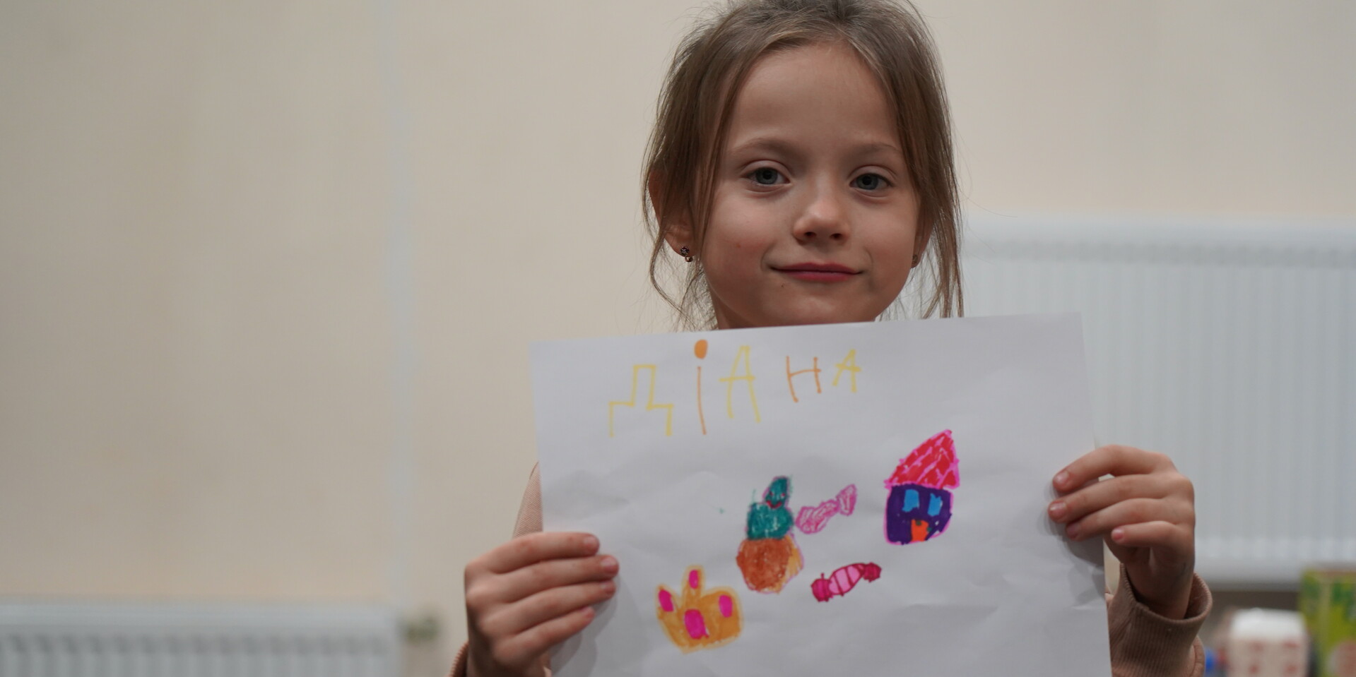 Ein Mädchen hält einen selbstgemalten Wunschzettel hoch