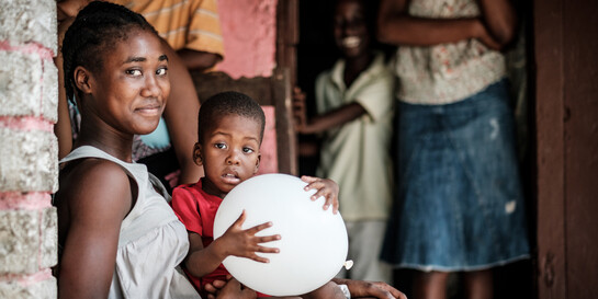 Eine Frau hat in Haiti einen Jungen auf ihrem Schoß sitzen
