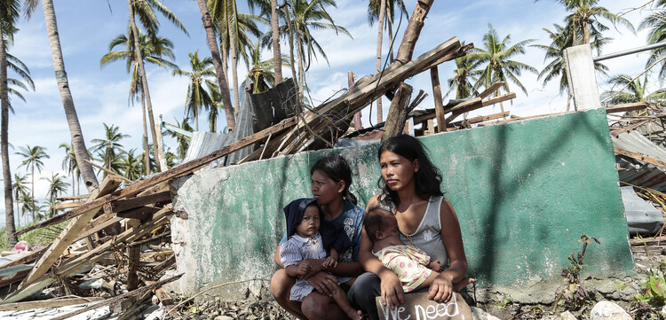 Nach dem schweren Taifun Haiyan auf den Philippinen sind viele Menschen von der Hilfe abgeschnitten. Zwei Frauen warten mit ihren Kindern auf Hilfe.