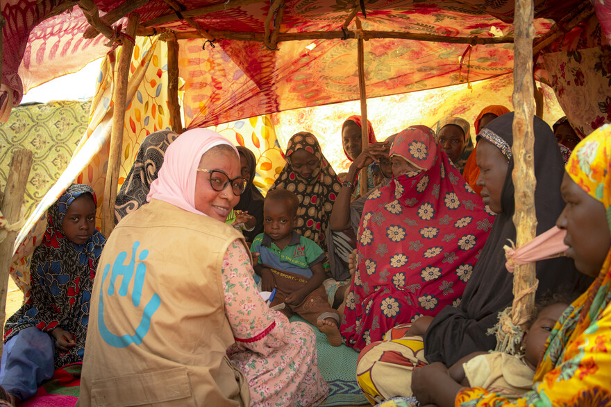 Eine Helferin sitzt bei geflüchteten Frauen in Mali in einem Zelt