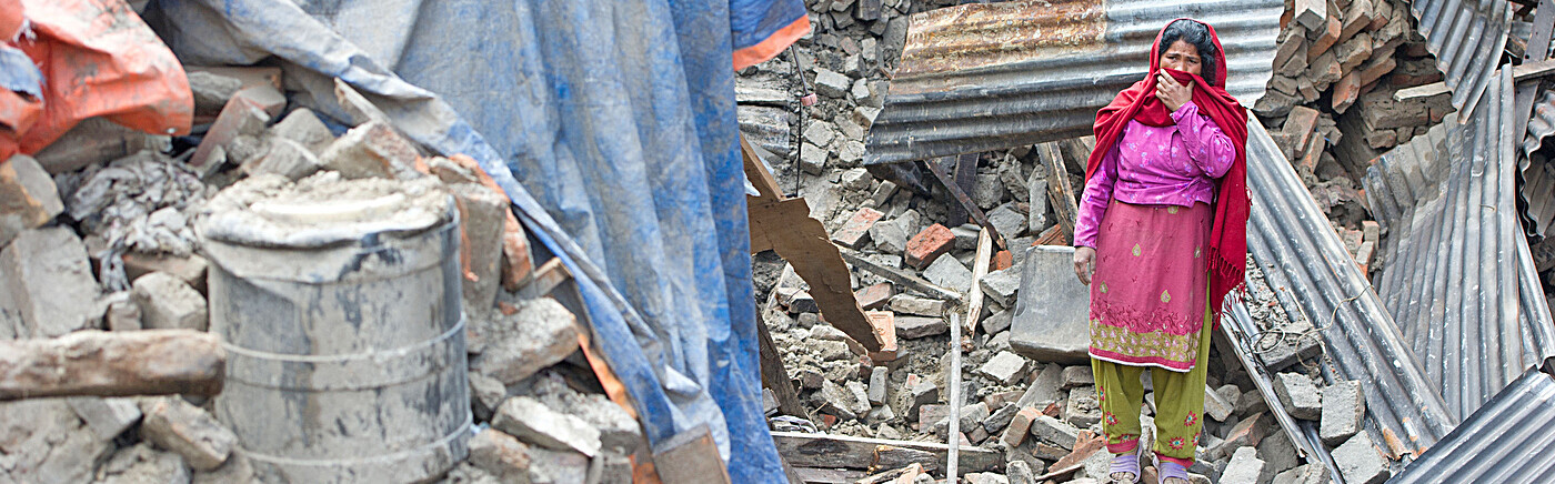 Eine Frau steht in Trümmern nach dem Erdbeben in Nepal