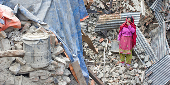 Eine Frau steht in Trümmern nach dem Erdbeben in Nepal