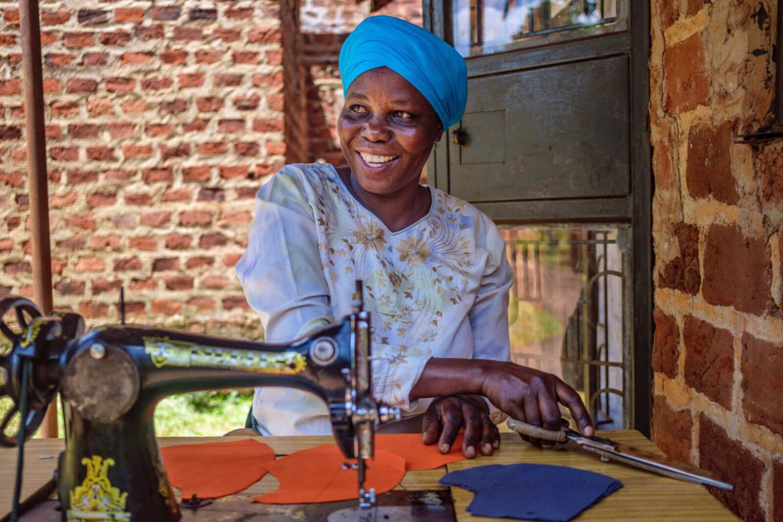 Eine Frau in Uganda sitzt an der Nähmaschine